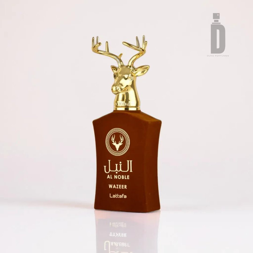The Al Noble Wazeer 100ml EDP by Lattafa perfume bottle features a gold deer head as its cap, exuding regal elegance. The brown bottle is adorned with white Arabic and English text, set against a plain, light gradient background with a "D" logo in the top-right corner, epitomizing luxury fragrance.