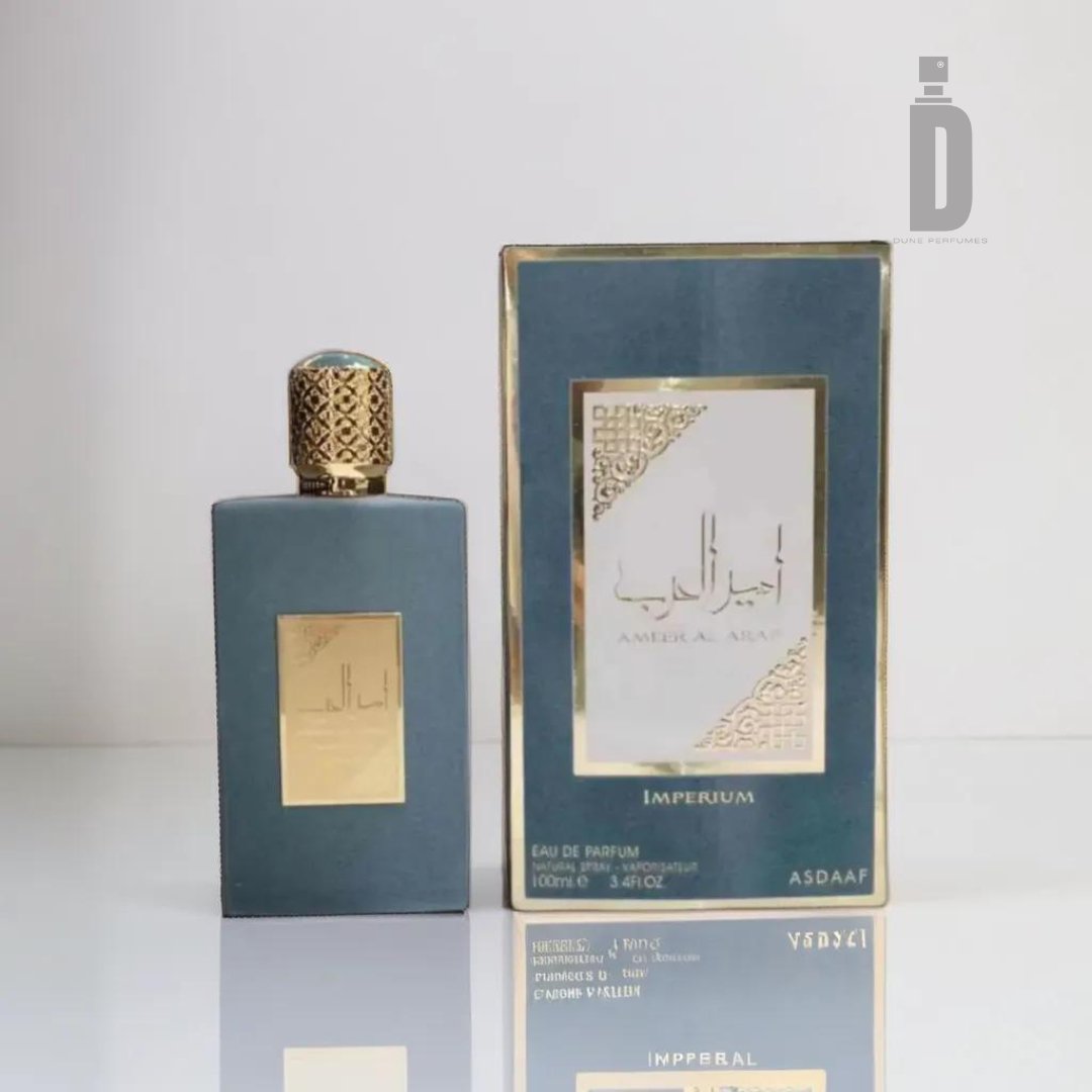 A cologne bottle and its packaging are displayed. The matte black bottle boasts a decorative gold cap and a gold label with Arabic text, prominently featuring the name "Ameer Al Arab Imperium 100ml EDP - Asdaaf." The box is elegantly designed in black and gold, with matching text and graphics that leave a lasting impression. The sophisticated fragrance's logo, "Asdaaf," is subtly visible at the bottom, under the renowned Lattafa brand.