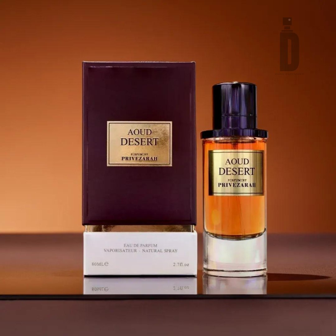 A box and bottle of Aoud Desert 80ml EDP by Paris Corner are displayed against a brown background. The rectangular dark purple box with a gold label adds elegance, while the translucent bottle reveals the amber-colored liquid. This captivating fragrance evokes exotic landscapes, complemented by a matching gold label and black cap.