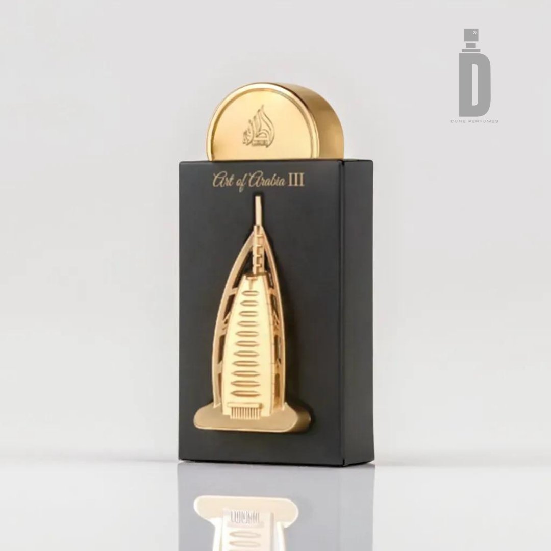 A perfume bottle designed with a tall, golden architectural structure that mirrors a modern skyscraper, set against a black rectangular base. At the top sits a rounded cap. Text on the upper part of the base reads "Art of Arabia III," evoking the exotic allure of an Arabian fragrance by Lattafa. This exquisite 100ml Eau De Parfum is known as Art of Arabia III 100ml EDP - Lattafa.
