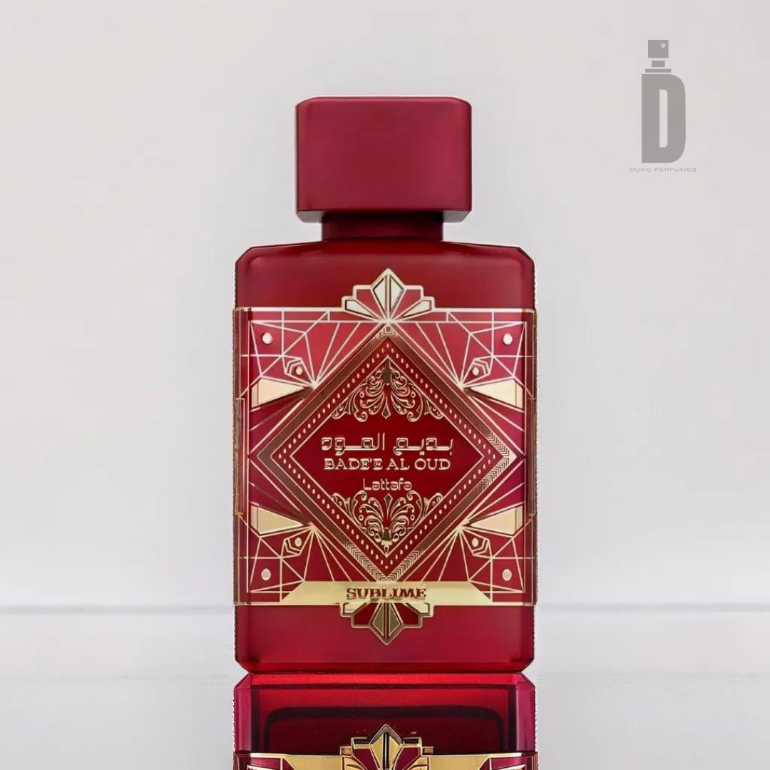 A luxurious red perfume bottle labeled "Badee Al Oud Sublime 100m EDP - Lattafa" features intricate gold geometric designs with the word "SUBLIME" elegantly displayed at the bottom. This bottle, from renowned brand Lattafa, exudes timeless elegance. Its reflections on the surface below hint at the enchanting fragrance it holds within.