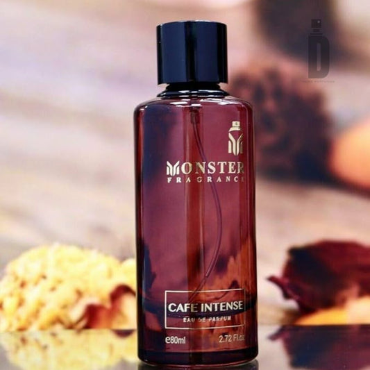 A brown-toned bottle of Paris Corner's "Cafe Intense 80ml EDP" stands on a blurred background. The sleek bottle, with a black cap and gold lettering, holds 80ml. Yellow and red flowers lie near the base, hinting at the floral notes that enrich this captivating fragrance.