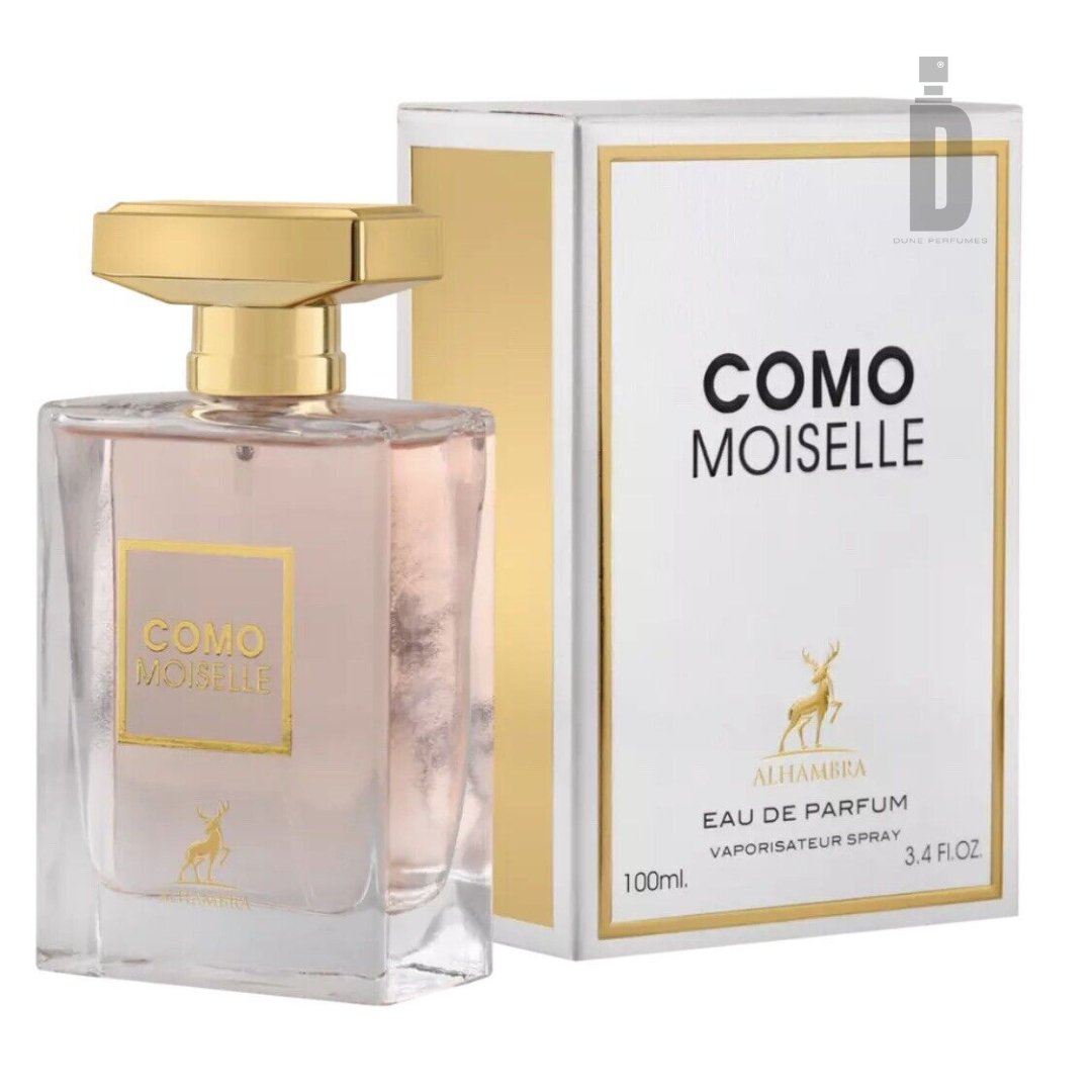 A rectangular perfume bottle with a gold cap and a clear pinkish liquid inside is shown next to its matching white and gold box. The text on the bottle and box reads "COMO MOISELLE" and "EAU DE PARFUM." This feminine fragrance by Maison Al Hambra, known as Como Moiselle 100ml EDP, contains 100ml (3.4 fl oz) with enchanting floral notes.