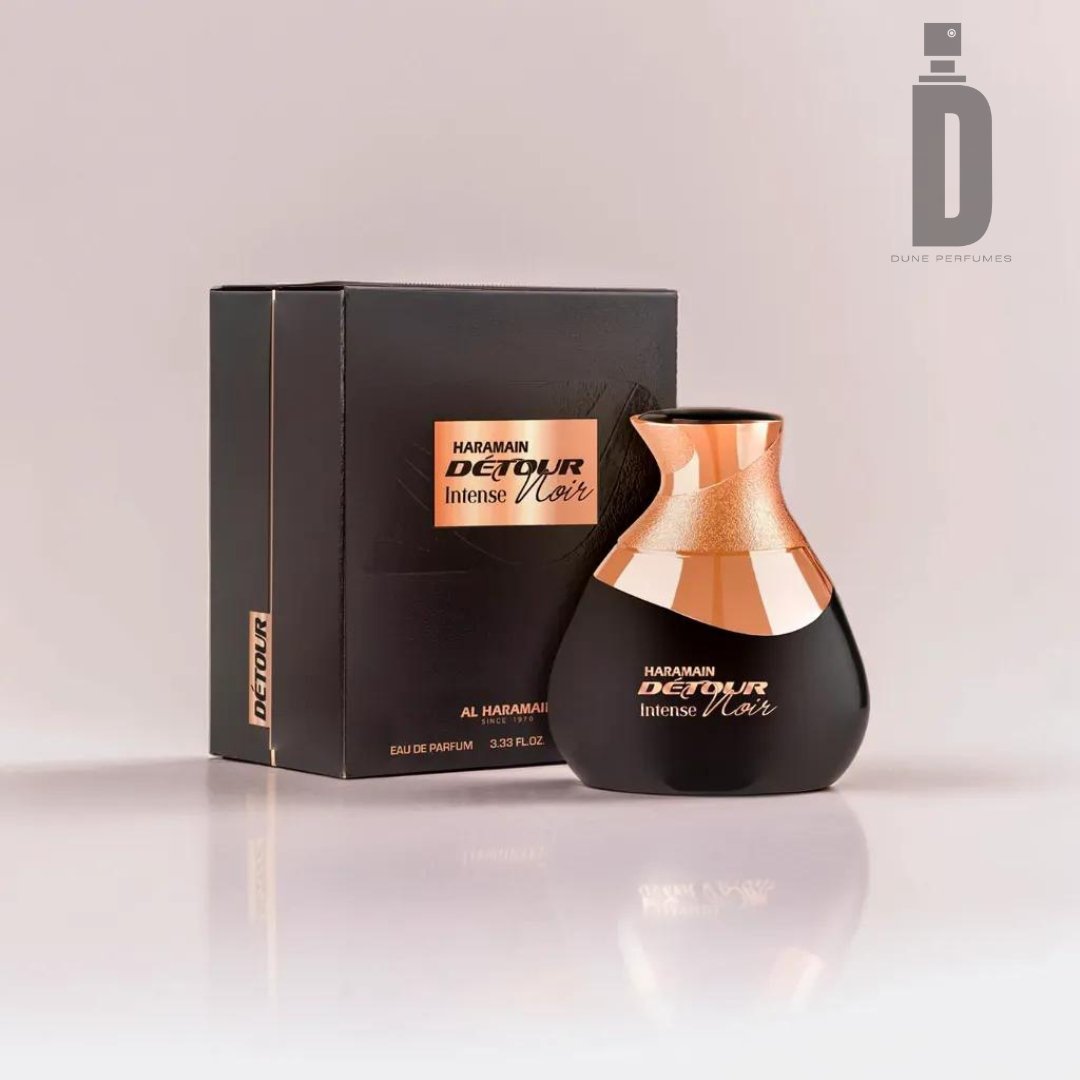 A bottle and box of Al Haramain's Detour Intense Noir 100ml EDP. The sleek, curved black bottle features copper accents, embodying a luxurious unisex fragrance. Matching the aesthetic, the black box is adorned with gold lettering and the Dune Perfumes logo in the top right corner.