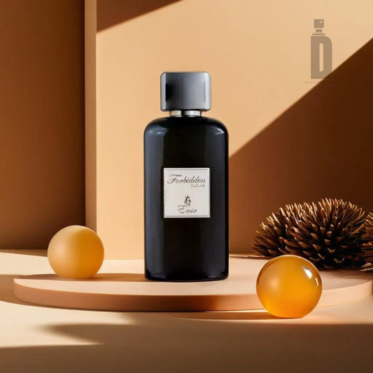 A sleek, dark bottle of cologne labeled "Forbidden Sugar 100ml EDP - Emir" from Paris Corner stands on a minimalist circular platform, exuding a sweet aroma that hints at caramel vanilla. It is surrounded by two amber spherical ornaments and a pinecone, set against a warm, tan-colored background with geometric shadows.
