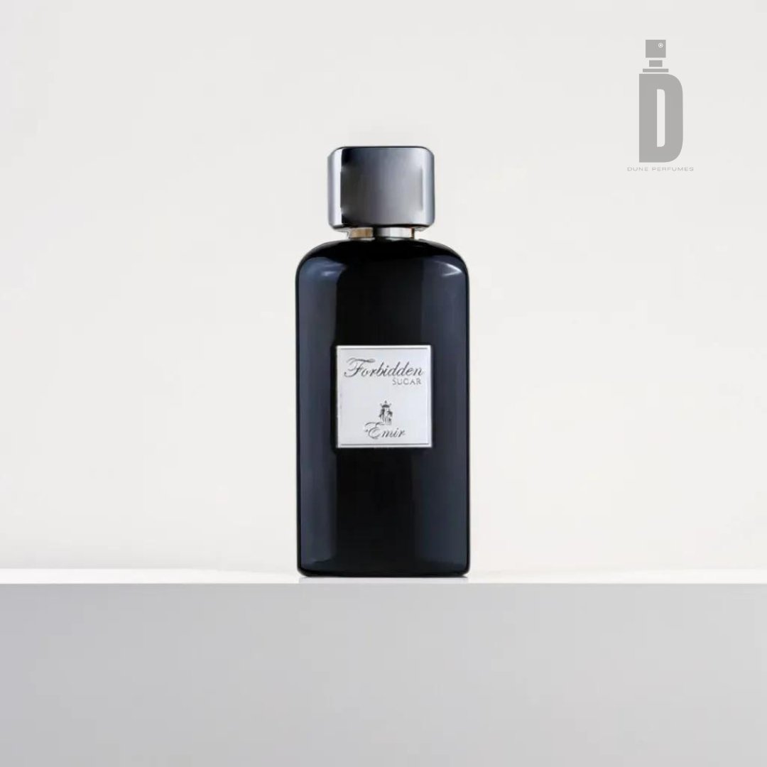 A sleek black bottle of "Forbidden Sugar" body wash by Paris Corner, featuring a metallic cap, is placed on a white surface against a simple white background. The label on the front of the bottle includes the brand name and product details, hinting at its sweet aroma of caramel vanilla.
