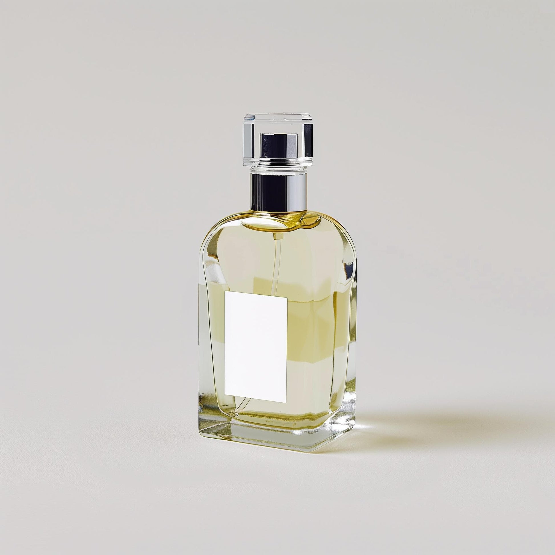 A clear glass bottle of "Example product" by Dune Perfumes, with a shiny silver cap and light yellow liquid, stands upright on a plain light background. A blank white label is displayed on the front of the bottle.