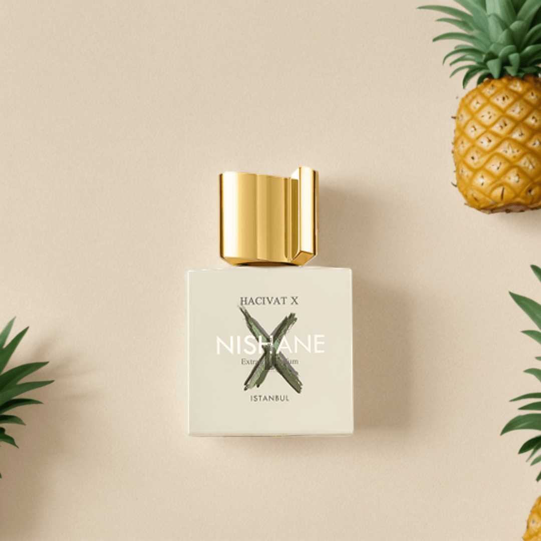 The Nishane Hacivat X 100ml EDP bottle with a gold cap rests on a beige background, accented by pineapples and green leaves, reflecting the elegant citrus-floral essence of this Nishane fragrance.