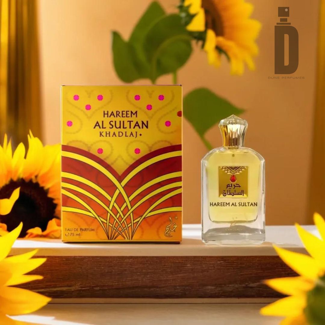 A bottle of Hareem Al Sultan Gold Spray 75ml EDP by Khadlaj is displayed next to its vibrant yellow and gold packaging. Set on a wooden surface, with sunflowers and green leaves in the background, this TikTok-inspired fragrance effortlessly captures attention.