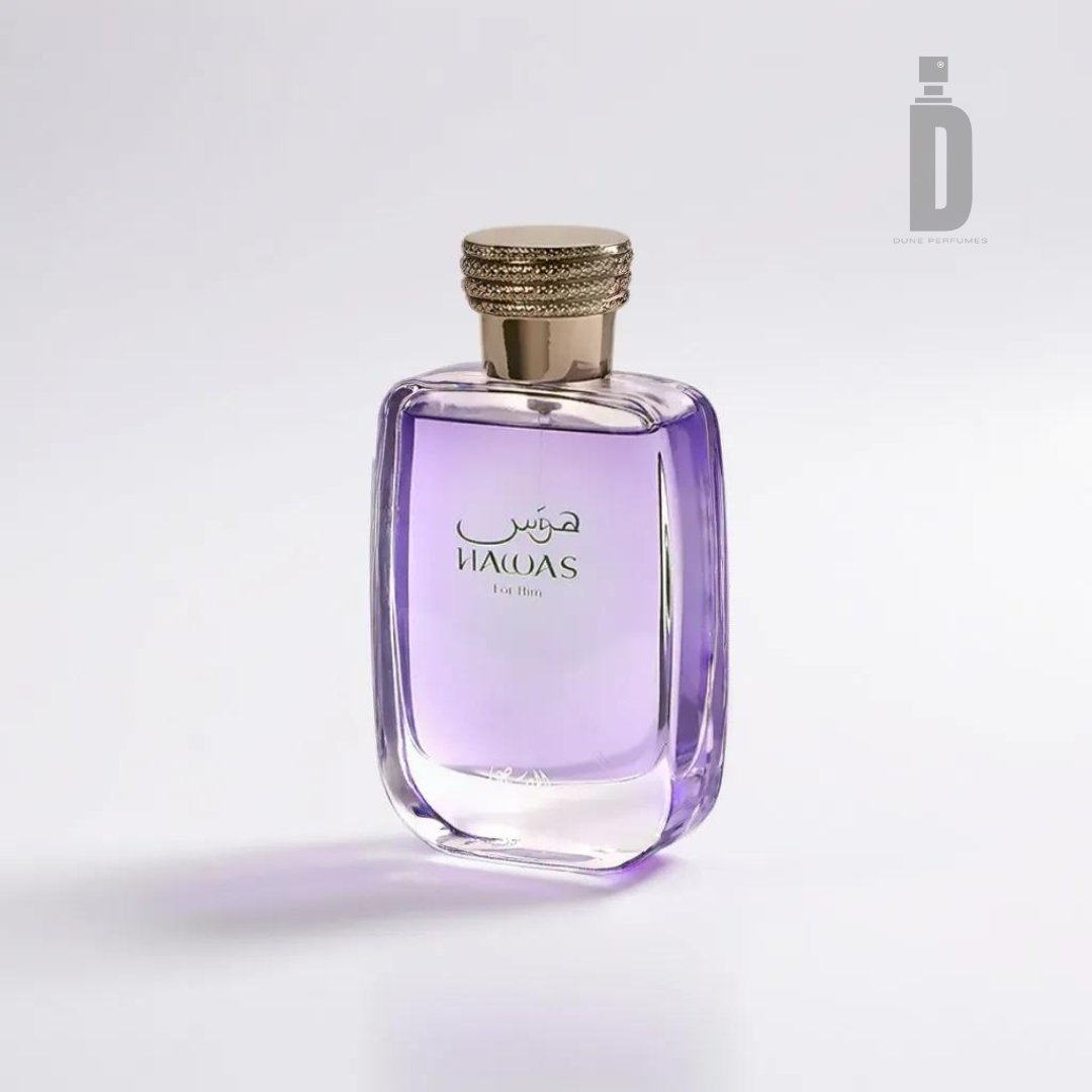 A transparent glass perfume bottle containing a light purple liquid, featuring a gold cap. The front of the bottle showcases Arabic script and the word "NAFAS," beautifully evoking an essence of adventure and allure against a plain white background. This is the Hawas 100ml EDP by Rasasi.