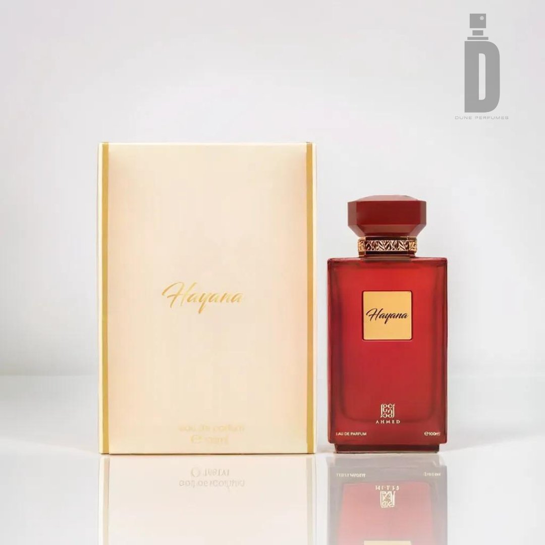 A rectangular red perfume bottle labeled "Hayana" by Ahmed Al Maghribi stands next to its matching beige box, exuding exotic charm. Both items are set against a neutral background. The bottle has a geometric cap, and the box features the brand's logo and text in elegant script.