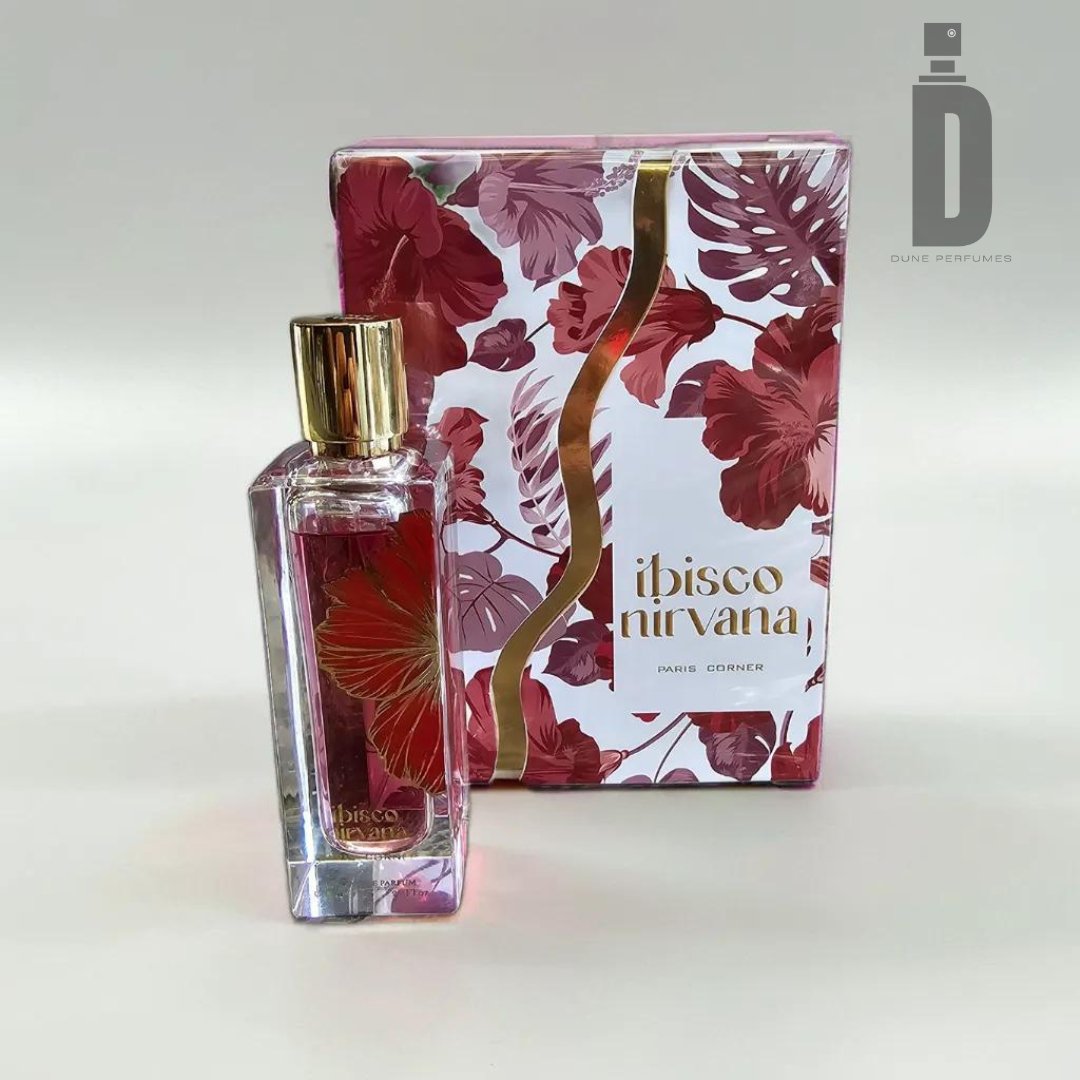 The Ibisco Nirvana 65ml EDP by Paris Corner features a rectangular perfume bottle with a gold cap, sitting in front of its matching box. Both the box and the bottle are adorned with red and pink floral designs reminiscent of hibiscus blooms. The names "Ibisco Nirvana" and "Paris Corner" are elegantly displayed in gold lettering, highlighting this luxurious fragrance.