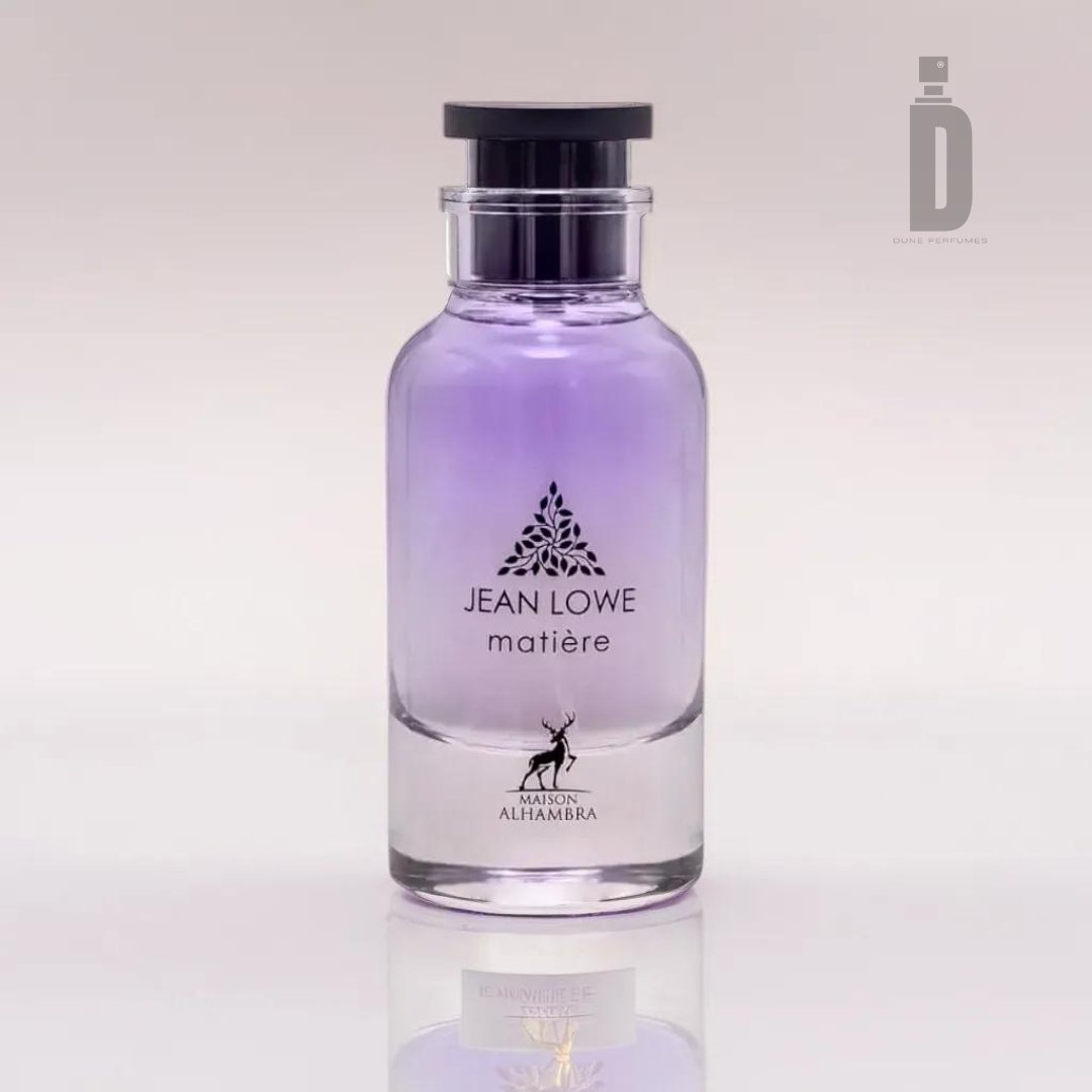 A clear glass perfume bottle with a gradient of purple liquid inside. The label reads "Jean Lowe Maitre (Matiere) 100ml EDP - Maison Alhambra," accompanied by a floral logo above. The bottle is topped with a black, cylindrical cap. This captivating fragrance from Maison Al Hambra exemplifies olfactory artistry against a plain, light-colored background.