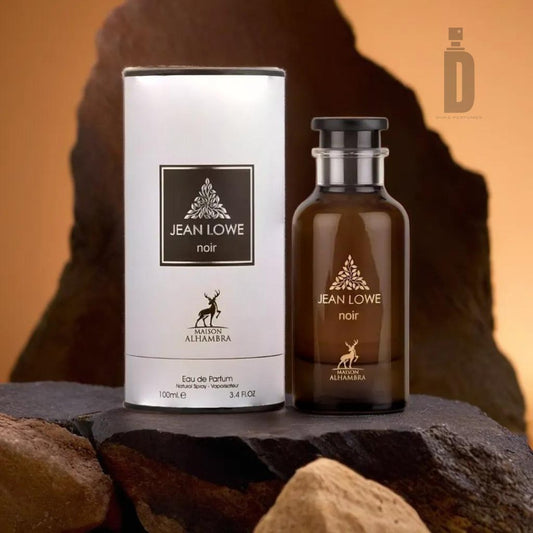 A bottle of Jean Lowe Noir (Ombre) 100ml Eau de Parfum by Maison Al Hambra, a sophisticated blend, is positioned on a rocky surface next to its cylindrical packaging. The amber bottle with a black label and cap contrasts elegantly with the white packaging, both featuring the same sleek design.