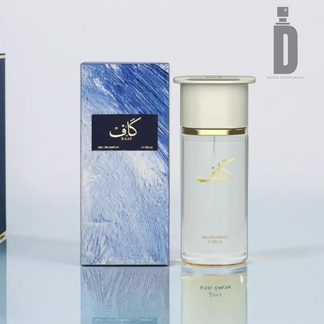 A clear perfume bottle with a white cap and gold Arabic text stands next to a blue and white textured box. "Kaaf 100ml EDP" by Ahmed Al Maghribi embodies an elegant fragrance with aquatic freshness. The brand logo appears in the top right corner.