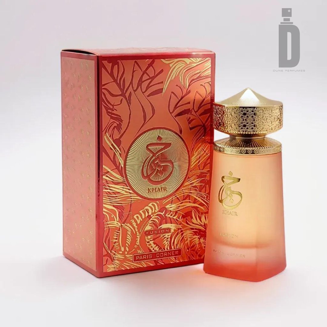 An exquisite 100ml bottle of Khair Fusion Eau de Parfum by Paris Corner comes with a matching red box, intricately adorned with gold designs and text, showcasing the brand's distinguished logo. The translucent perfume bottle features an elegant ombré design, transitioning from pale yellow to deep red, and is topped with a textured gold cap. Indulge in the alluring floral and fruity notes of this enchanting fragrance.