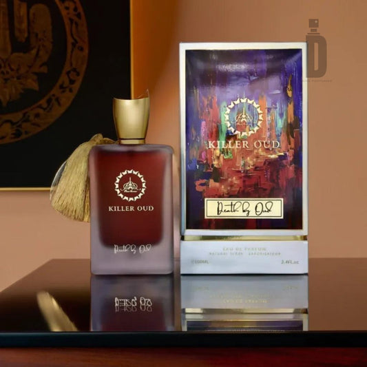 A bottle of "Killer Oud Death by Oud" fragrance from Paris Corner, adorned with a gold cap and tassel, sits on a reflective surface next to its vibrant, decorative packaging. The box features colorful abstract artwork and the same gold logo as seen on the "Death by Oud" perfume bottle.