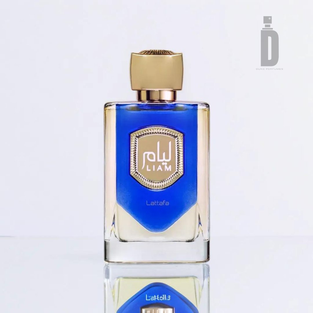 A clear rectangular bottle of Liam Blue Shine 100ml EDP - Lattafa featuring vibrant blue liquid, a gold cap, and an ornate gold and white label with "LIAM" at the center. The bottle, which bears the brand name "Lattafa" at the bottom, sits on a reflective surface exuding an invigorating freshness.