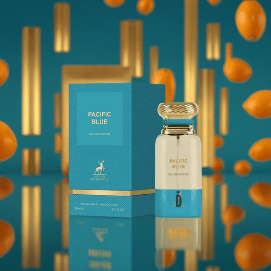 The Pacific Blue 80ml EDP by Maison Alhambra is showcased with its blue and gold packaging, set against a blue backdrop with floating golden cylinders and orange fruits, evoking the fresh allure of ocean breezes.