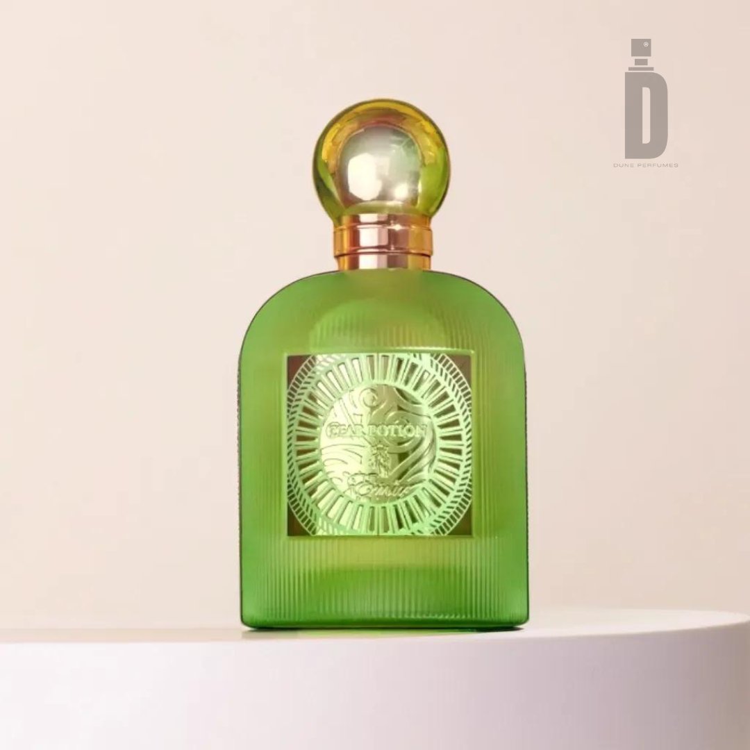 A green bottle of "Pear Potion 100ml EDP" by Paris Corner, adorned with a gold spherical cap, is elegantly showcased against a beige background. The intricately designed bottle features a sun motif on the front with the text “Eau de Parfum” prominently displayed in the center, emanating a subtle hint of fresh fruitiness.