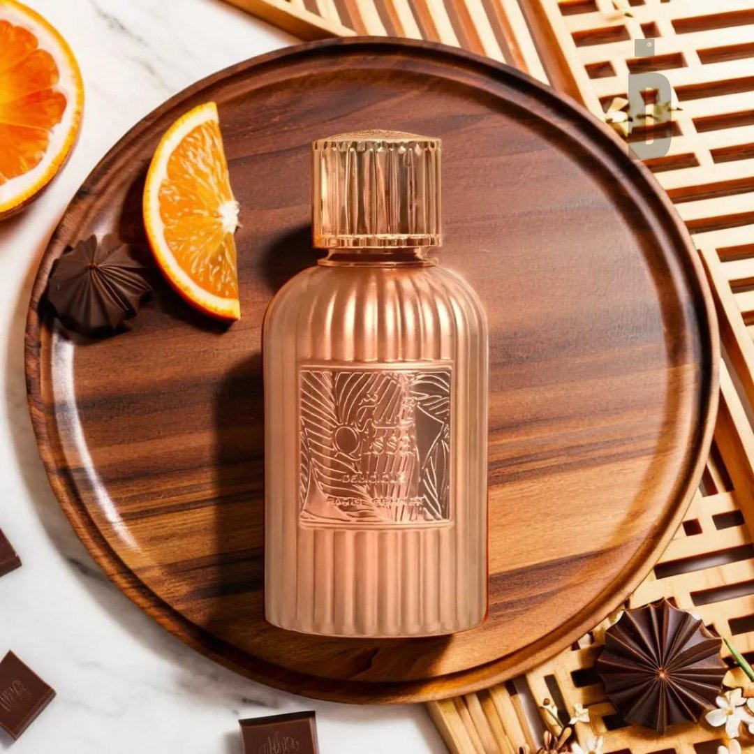 A beautifully designed glass perfume bottle sits on a round wooden tray. The ribbed bottle features a detailed, embossed label titled "Qissa Delicious 100ml EDP - Paris Corner" by Paris Corner. Surrounding the tray are orange slices, pieces of dark chocolate, and a geometric wooden ornament, evoking sweet moments connected to the fragrance.