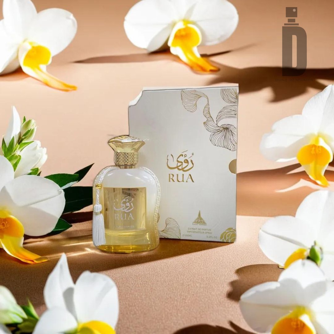 A bottle of Rua 100ml EDP - Paris Corner perfume stands beside its matching ornate box. The scene is artfully decorated with white and yellow flowers, exuding feminine elegance and creating an ambiance reminiscent of a Paris Corner.