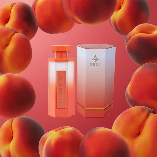The Pesca 200ml EDP by Reef features a perfume bottle and box in gradient orange hues, nestled with ripe peaches and iris flowers against a peach-colored backdrop, capturing summer's bountiful beauty.