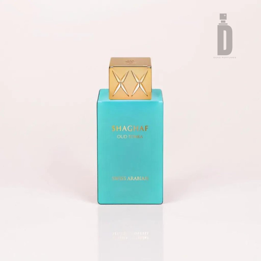 A 75ml EDP rectangular turquoise perfume bottle, named Shaghaf Oud Tonka by Swiss Arabian, features a gold cap and a sophisticated geometric pattern. The label displays "SHAGHAF OUD TONKA" in gold lettering with "SWISS ARABIAN" beneath it. Infused with notes of Turkish Rose and Cinnamon Bark, the bottle is set against a plain white background, highlighted by an uppercase "D" logo in the top right corner.