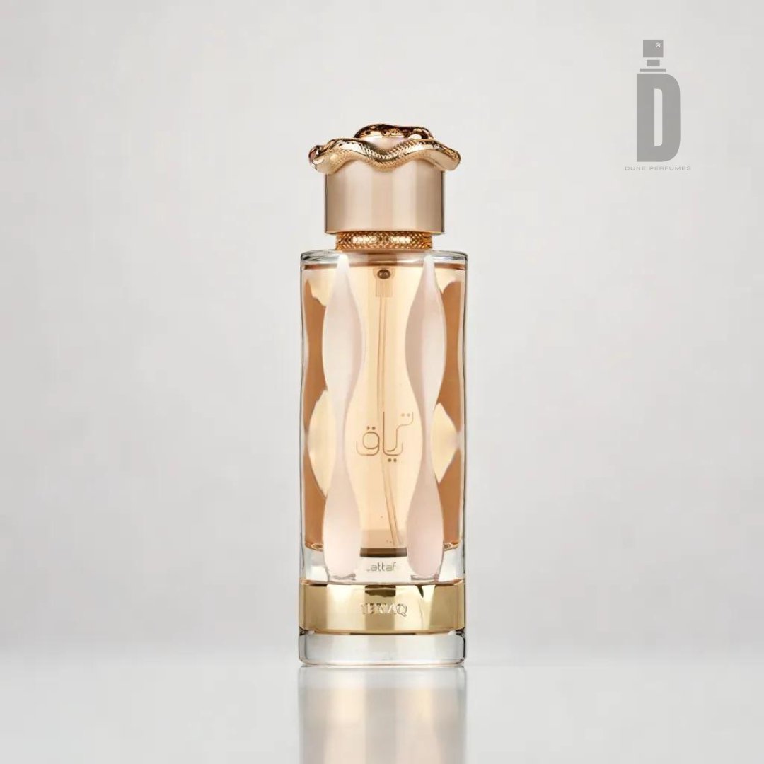 Here is the revised sentence incorporating the provided product data:

A luxurious perfume bottle with a wavy golden design and an ornate cap, featuring Arabic calligraphy on the front. The bottle, containing a captivating fragrance called "Teriaq 100ml EDP - Lattafa," is placed against a light gray background. The logo "D" and "Dunhill Perfumes" are visible in the upper right corner.