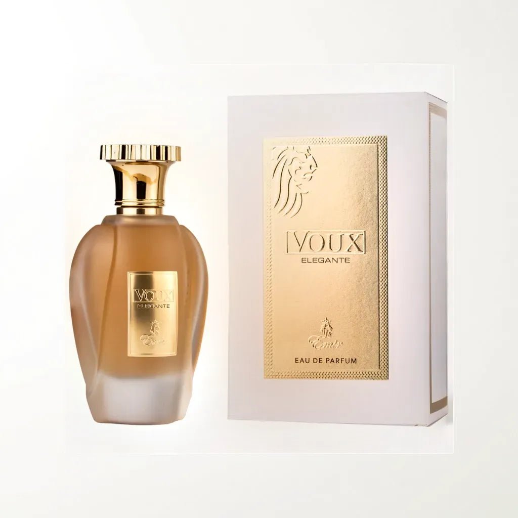 A perfume bottle labeled "Voux Elegante Emir 100ml EDP - Paris Corner" with a gold cap stands next to its matching gold and white box, exuding timeless elegance. Both the bottle and the box feature a lion head logo and text indicating it is an Eau de Parfum. The background is plain white, highlighting the refined fragrance from Paris Corner.
