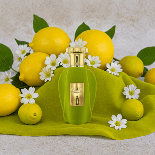 The Voux Zingy 100ml EDP by Paris Corner sits on green cloth, framed by lemons, green leaves, and white daisies—suggesting a fresh, citrus scent—against a neutral background.