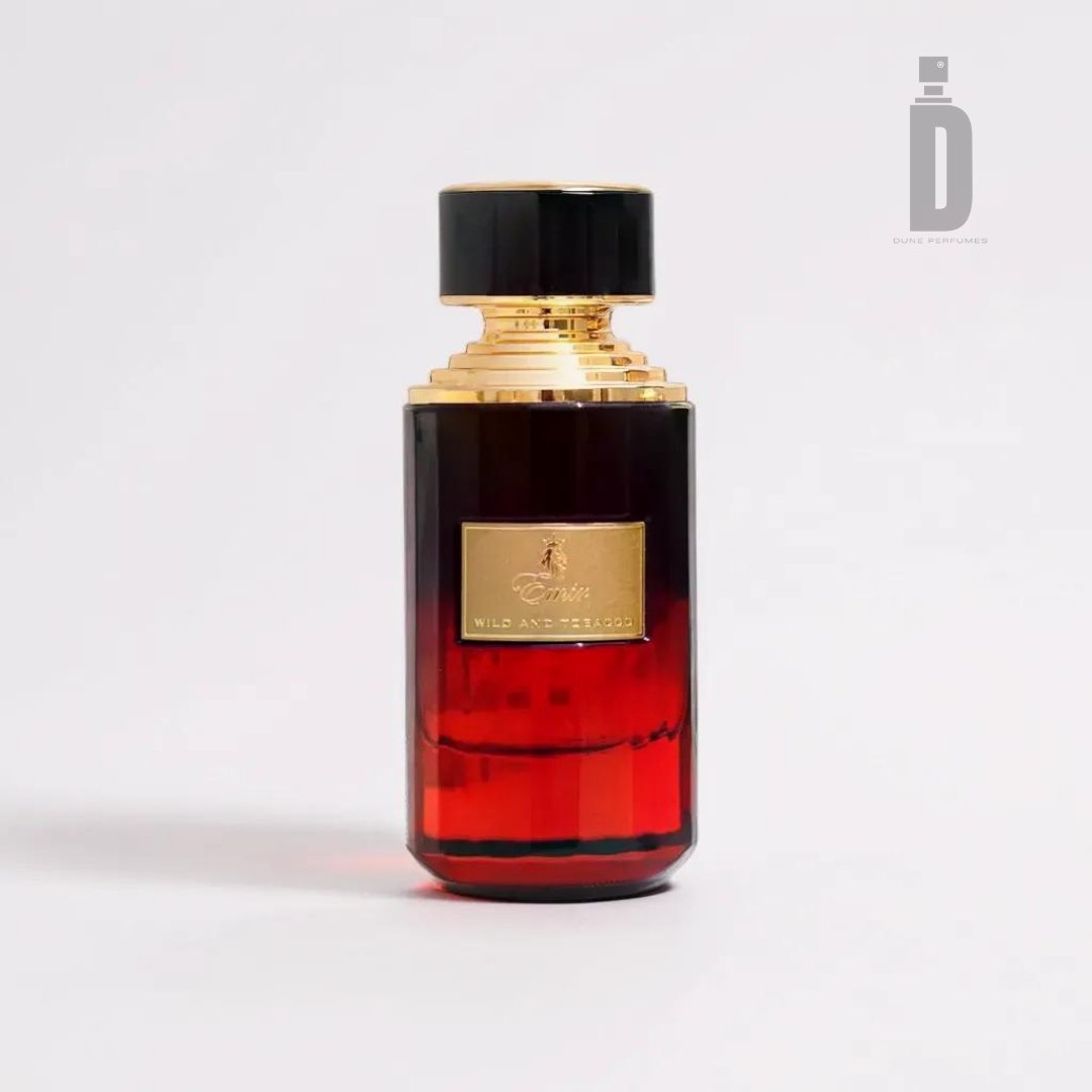 A luxury perfume bottle with a rectangular shape and a black rounded cap, branded as "Wild and Tobacco 75ml EDP - Emir" by Paris Corner. The bottle transitions from dark at the top to a rich red at the bottom, encapsulating the bold "Wild and Tobacco" fragrance. A gold label on the front reads "Wild and the Oud." The background is plain and light-colored.